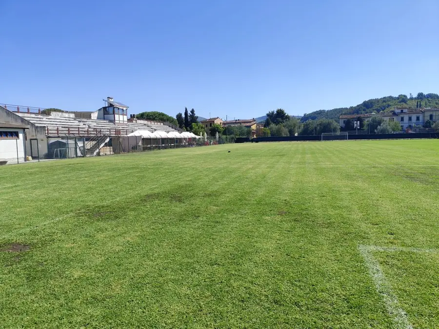 Il campo con la tribuna e il punto ristoro del circolo sullo sfondo