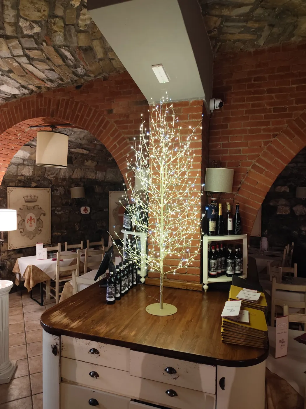 Albero di luce bianco caldo sul banco di un ristorante con volte in mattoni e pietra